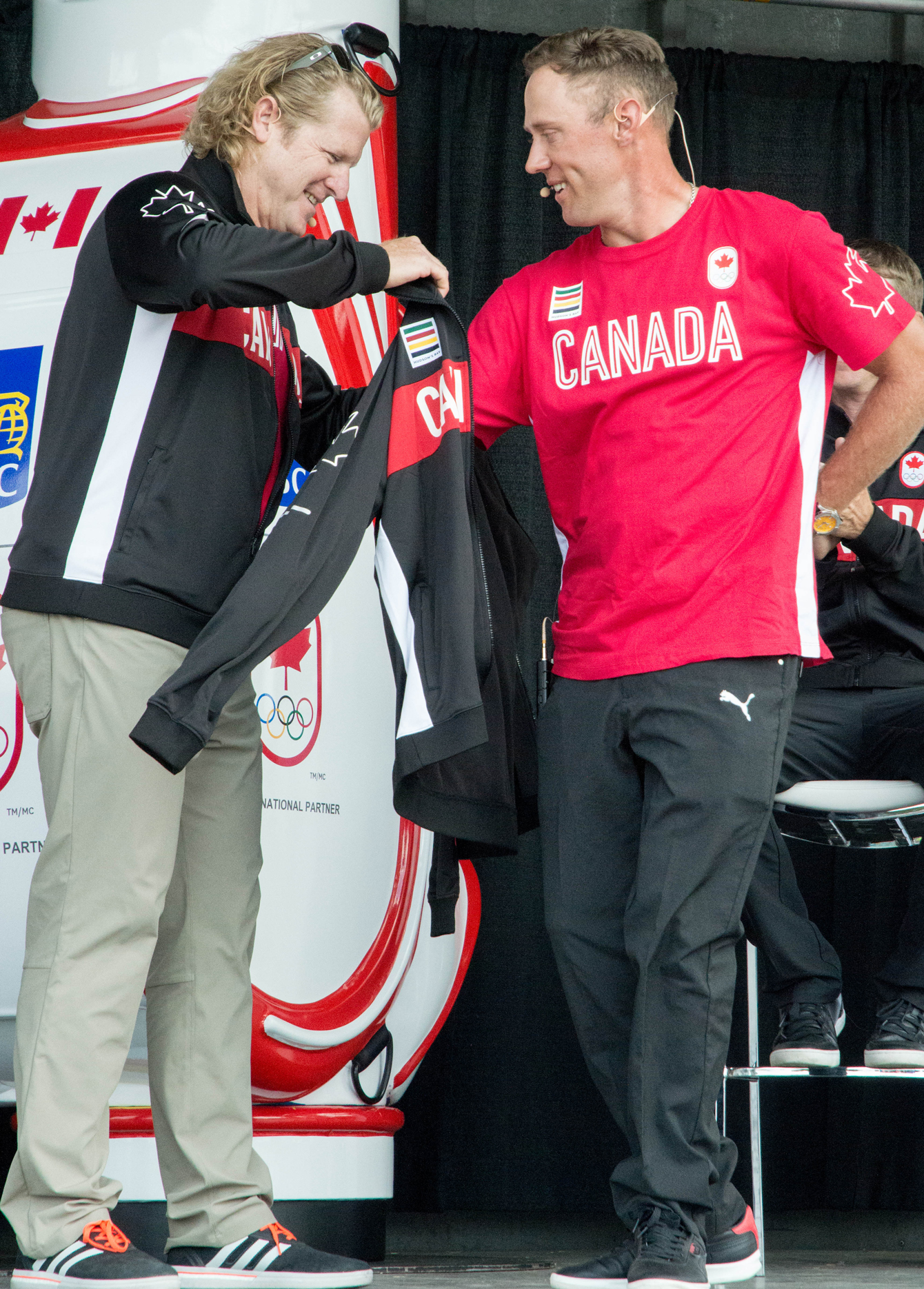 Curt Harnett, Team Canada's chef de mission, gives golfer Graham DeLaet his Olympic jacket at the Glen Abbey Golf Club on July 19, 2016. (Tavia Bakowski/COC)