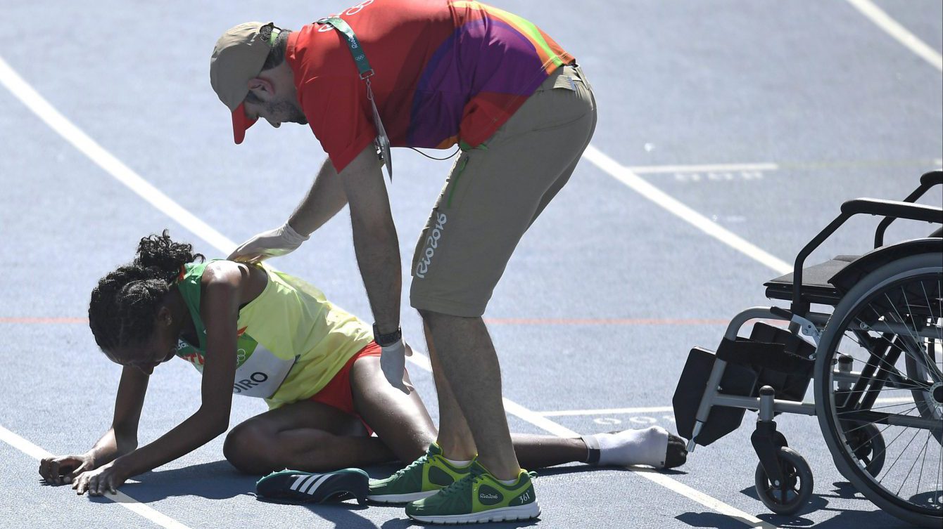 Ethiopia's Etenesh Diro is helped on the track after a women's 3000-meter steeplechase heat during the athletics competitions of the 2016 Summer Olympics at the Olympic stadium in Rio de Janeiro, Brazil, Saturday, Aug. 13, 2016. (AP Photo/Martin Meissner)