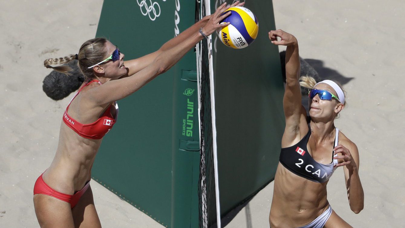 Sarah Pavan, left, blocks a shot from compatriot Kristina Valjas during a women's beach volleyball round of 16 match at the 2016 Summer Olympics in Rio de Janeiro, Brazil, Saturday, Aug. 13, 2016. (AP Photo/Marcio Jose Sanchez)