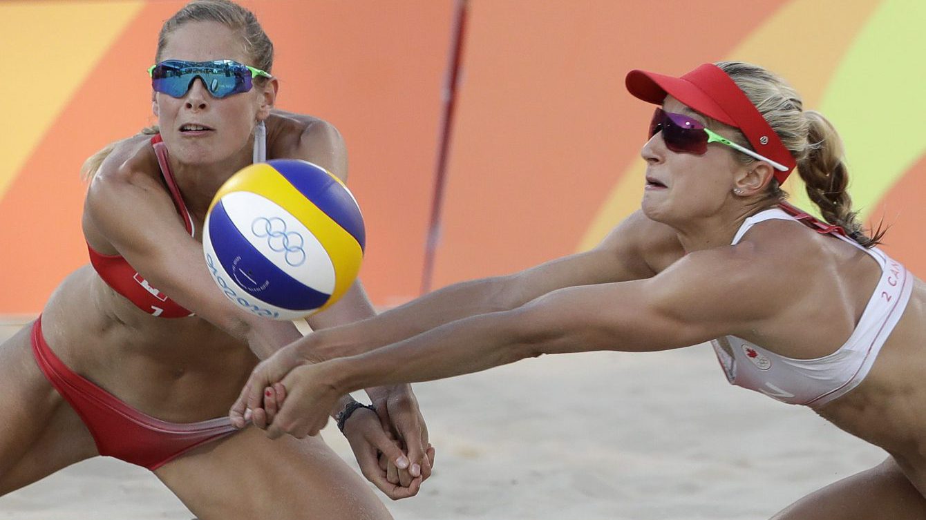 Canada's Sarah Pavan, left, and Heather Bansley dig together against Germany during a women's beach volleyball quarterfinal match at the 2016 Summer Olympics in Rio de Janeiro, Brazil, Sunday, Aug. 14, 2016. (AP Photo/Marcio Jose Sanchez)