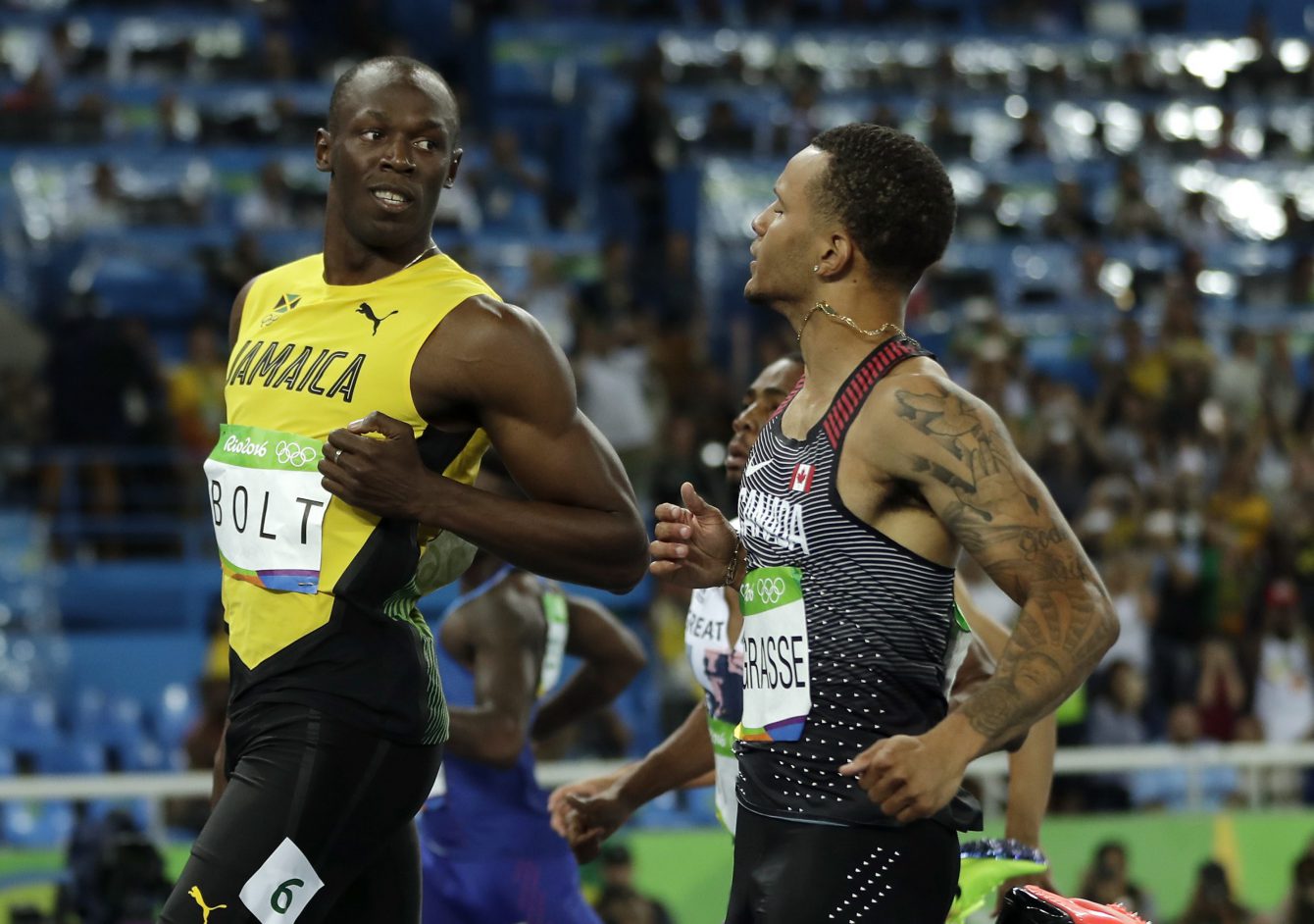 Jamaica's Usain Bolt, left, looks to Canada's Andre De Grasse after crossing the line during a men's 100-meter semifinal during the athletics competitions in the Olympic stadium of the 2016 Summer Olympics in Rio de Janeiro, Brazil, Sunday, Aug. 14, 2016. (AP Photo/Matt Slocum)