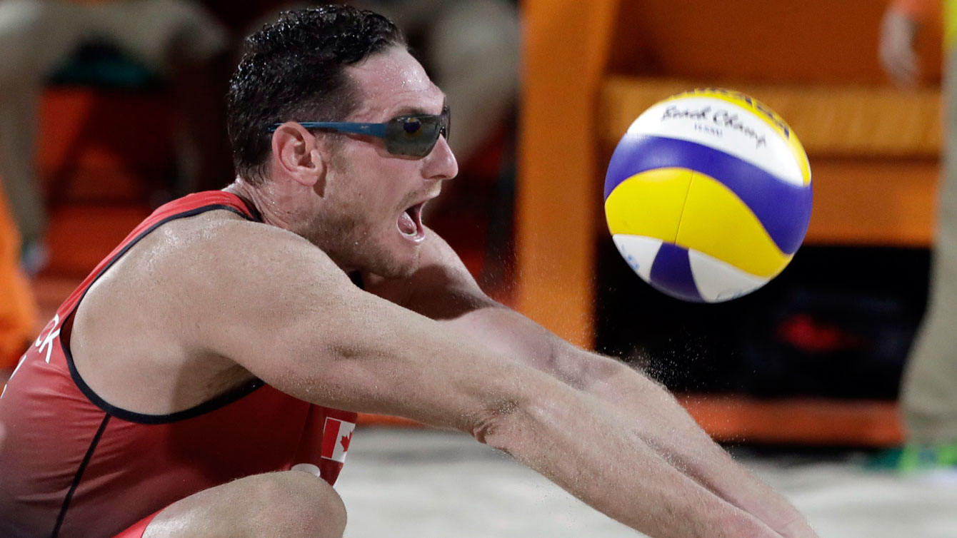 Canada's Josh Binstock digs against Italy during a men's beach volleyball match at the 2016 Summer Olympics in Rio de Janeiro, Brazil, Monday, Aug. 8, 2016. (AP Photo/Marcio Jose Sanchez)
