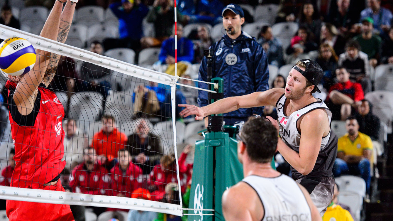 Sam Schachter attacks while Austria's Clemens Doppler blocks at the Rio 2016 beach volleyball tournament / Photo via FIVB