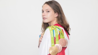 Canada's Penny Oleksiak poses with her medals on the flag at the Olympic games in Rio de Janeiro, Brazil, Sunday August 21, 2016. COC Photo/Mark Blinch
