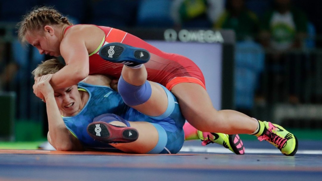 Eric Wiebe in red pins her opponent in blue to the wrestling mat
