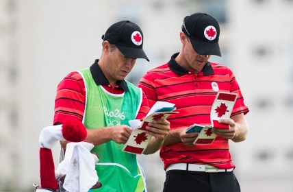 Canada's Graham Delaet, and his caddie Ray Whitney, look over notes during the first round of men's golf at the Olympic games in Rio de Janeiro, Brazil, Thursday August 11, 2016. COC Photo/Mark Blinch