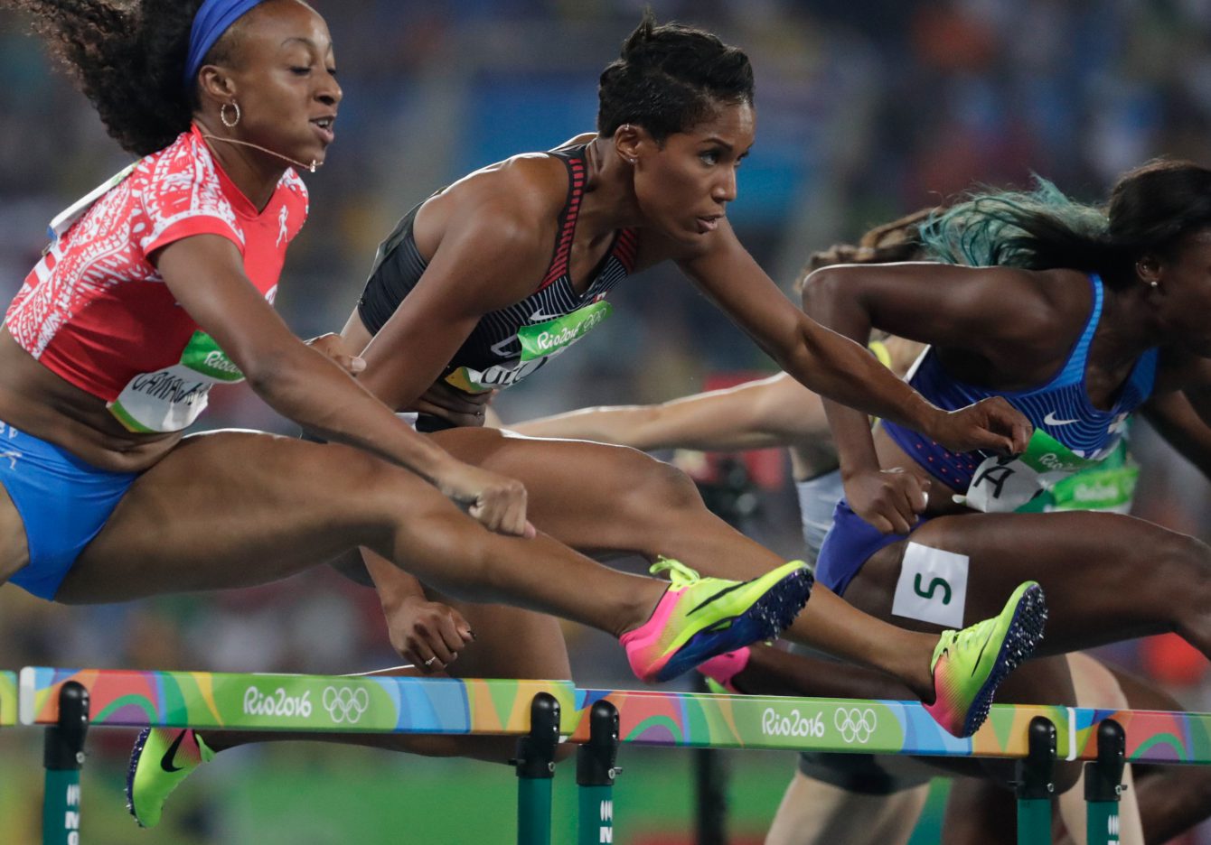 Several women leaping over hurdles