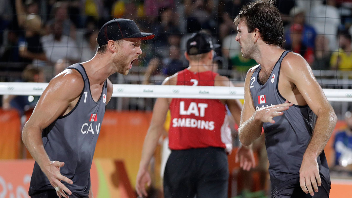 Canada's Ben Saxton, right, and Chaim Schalk, left, celebrate after winning a point during a men's beach volleyball match against Latvia at the 2016 Summer Olympics in Rio de Janeiro, Brazil, Monday, Aug. 8, 2016. (AP Photo/Petr David Josek)