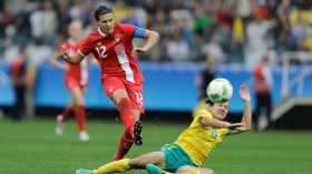 Sinclair kicking ball past sliding defender