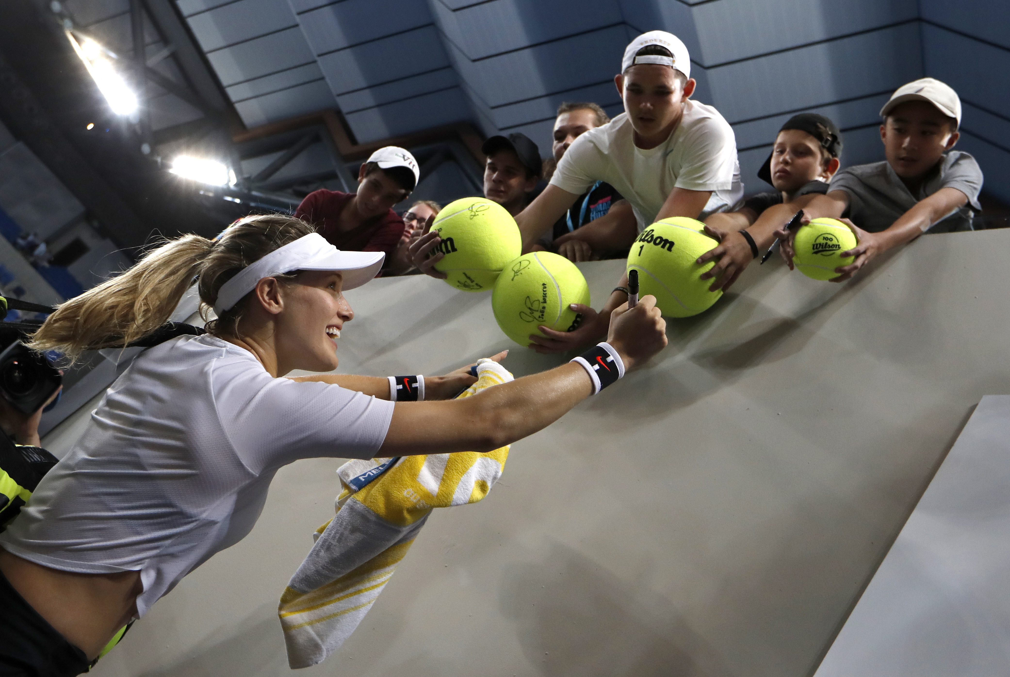 Canada's Eugenie Bouchard signs autographs for fans after defeating United States' Louisa Chirico in their first round match at the Australian Open tennis championships in Melbourne, Australia, Tuesday, Jan. 17, 2017. (AP Photo/Kin Cheung)