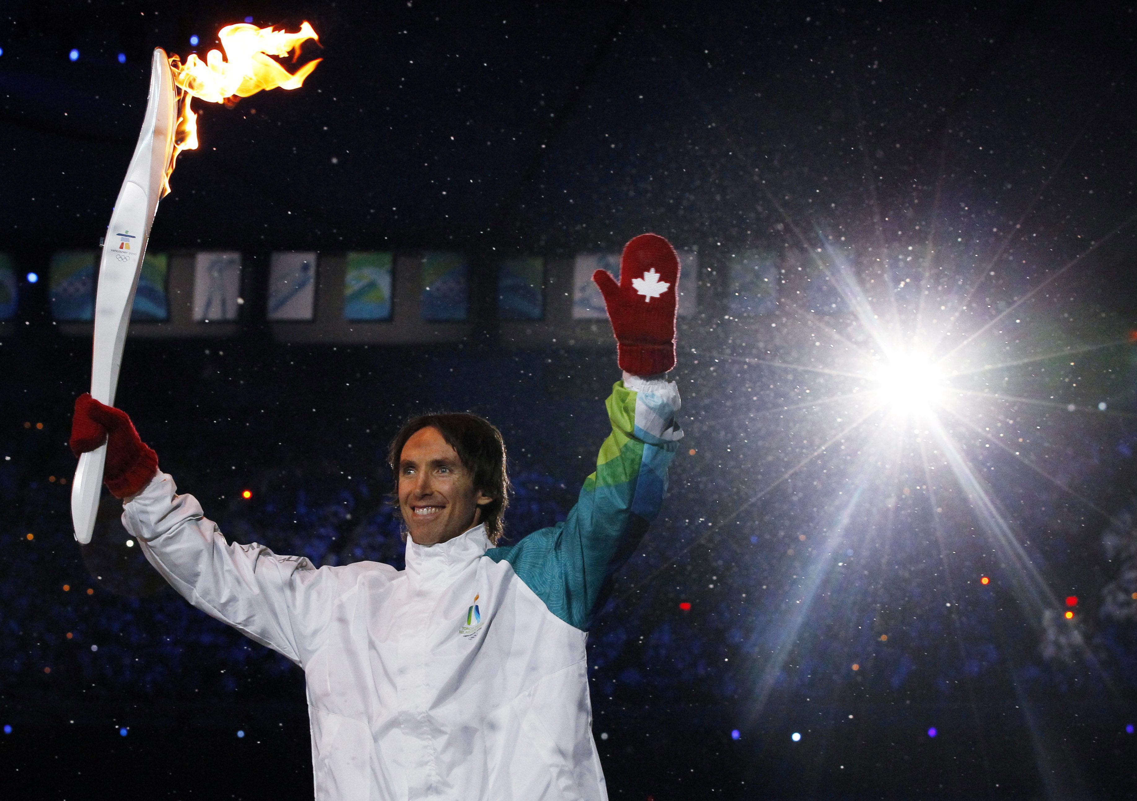 Torchbearer smiles as he waves to the crowd