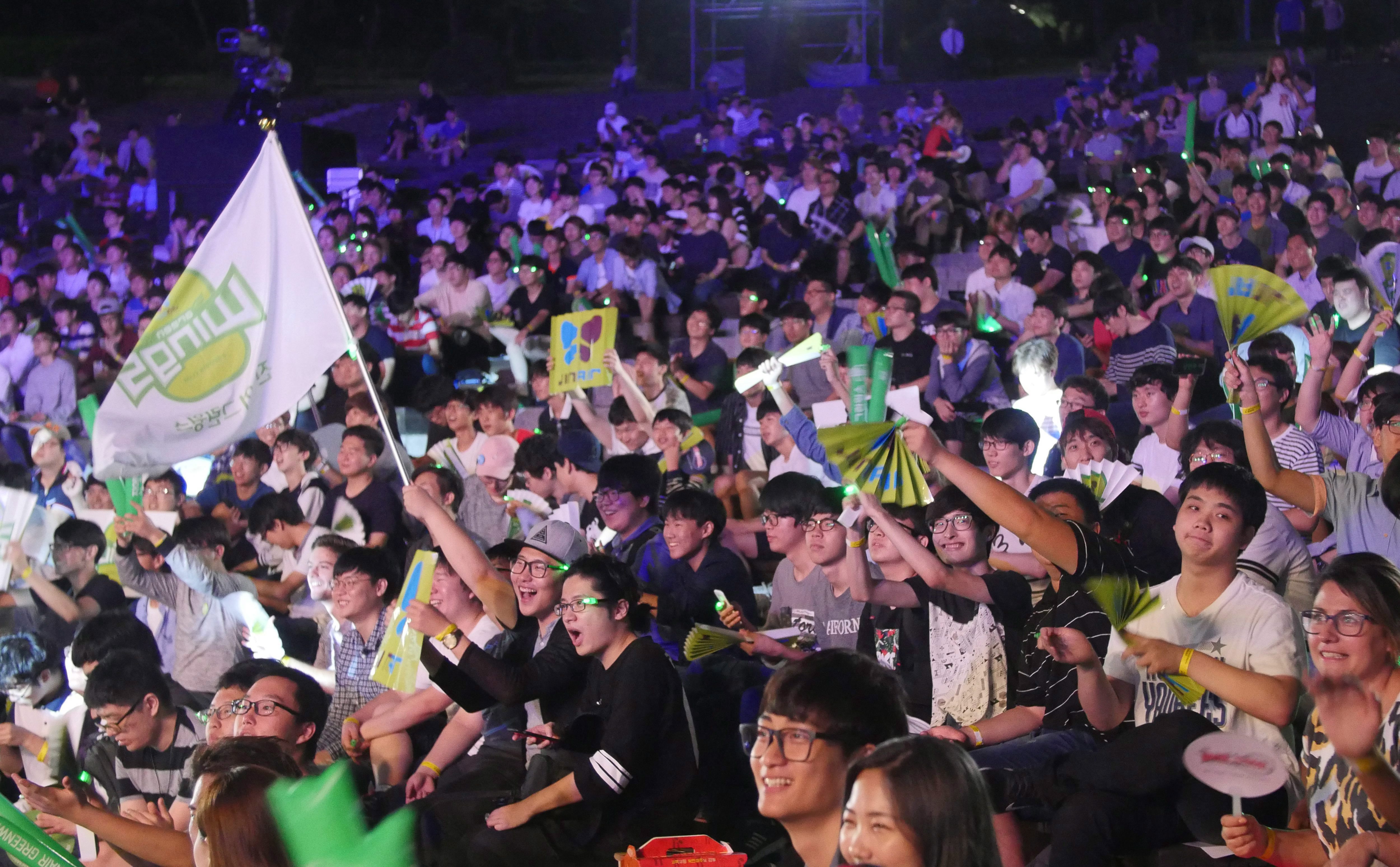 In this Sept. 3, 2016, photo, fans of Jin Air Green Wings celebrate the victory together after the 2016 SK Telecom StarCraft final match between KT Rolster and Jin Air Green Wings at Children's Grand park in Seoul, South Korea. South Korea has the biggest e-Sports industry in the world with professional leagues and broadcasting channels. (AP Photo/Jungho Choi)