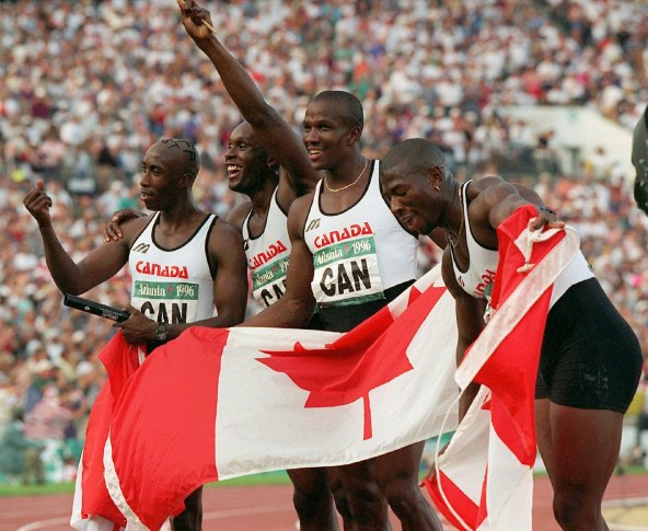 BAILEY ESMIE SURIN GILBERT Relay waving to crowd and holding Canadian flag