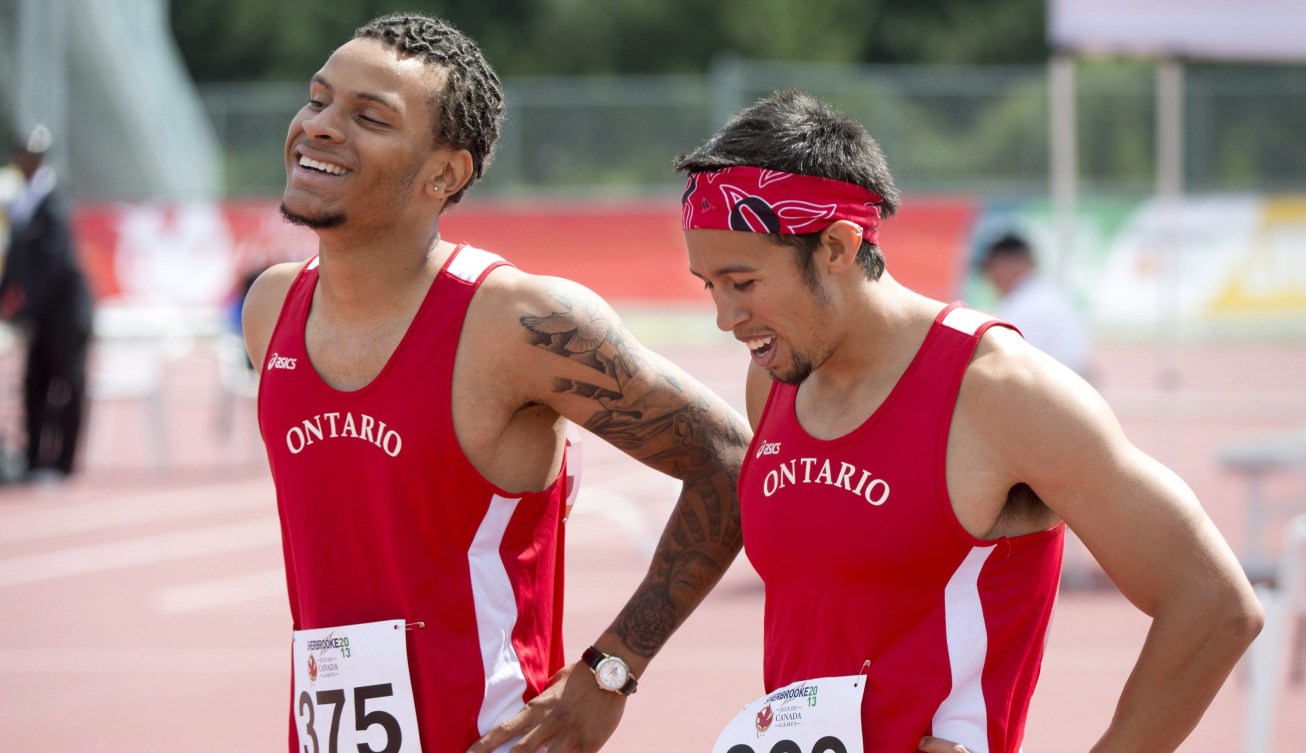 Two athletes in red Ontario singlets smile on the track