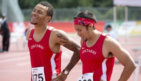 Two athletes in red Ontario singlets smile on the track