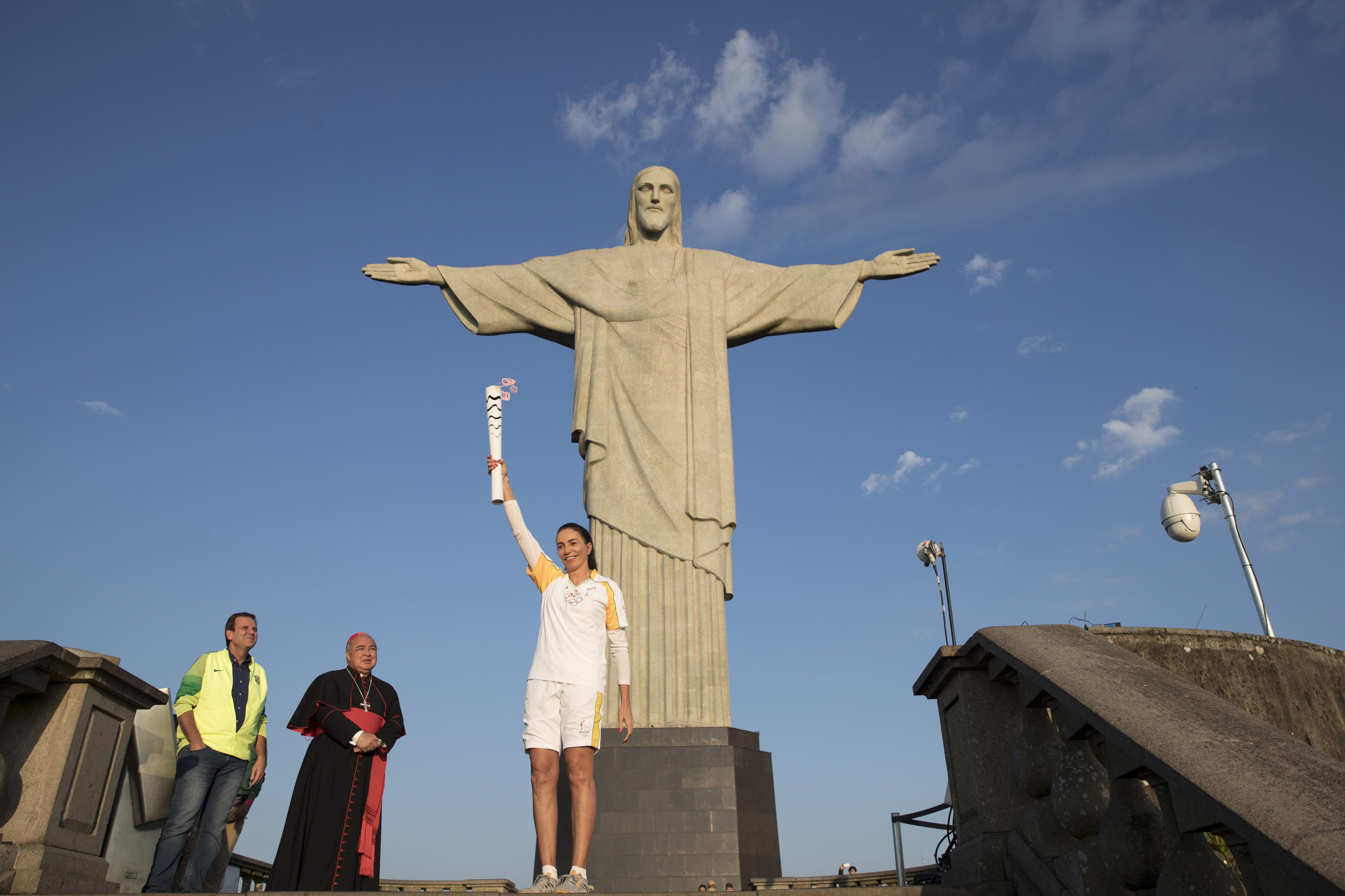 Brazil's Isabel Barroso Salgado carries the Olympic torch in front of the Christ the Redeemer statue on its way for the opening ceremony of Rio's 2016 Summer Olympics in Rio de Janeiro, Brazil, Friday, Aug. 5, 2016.