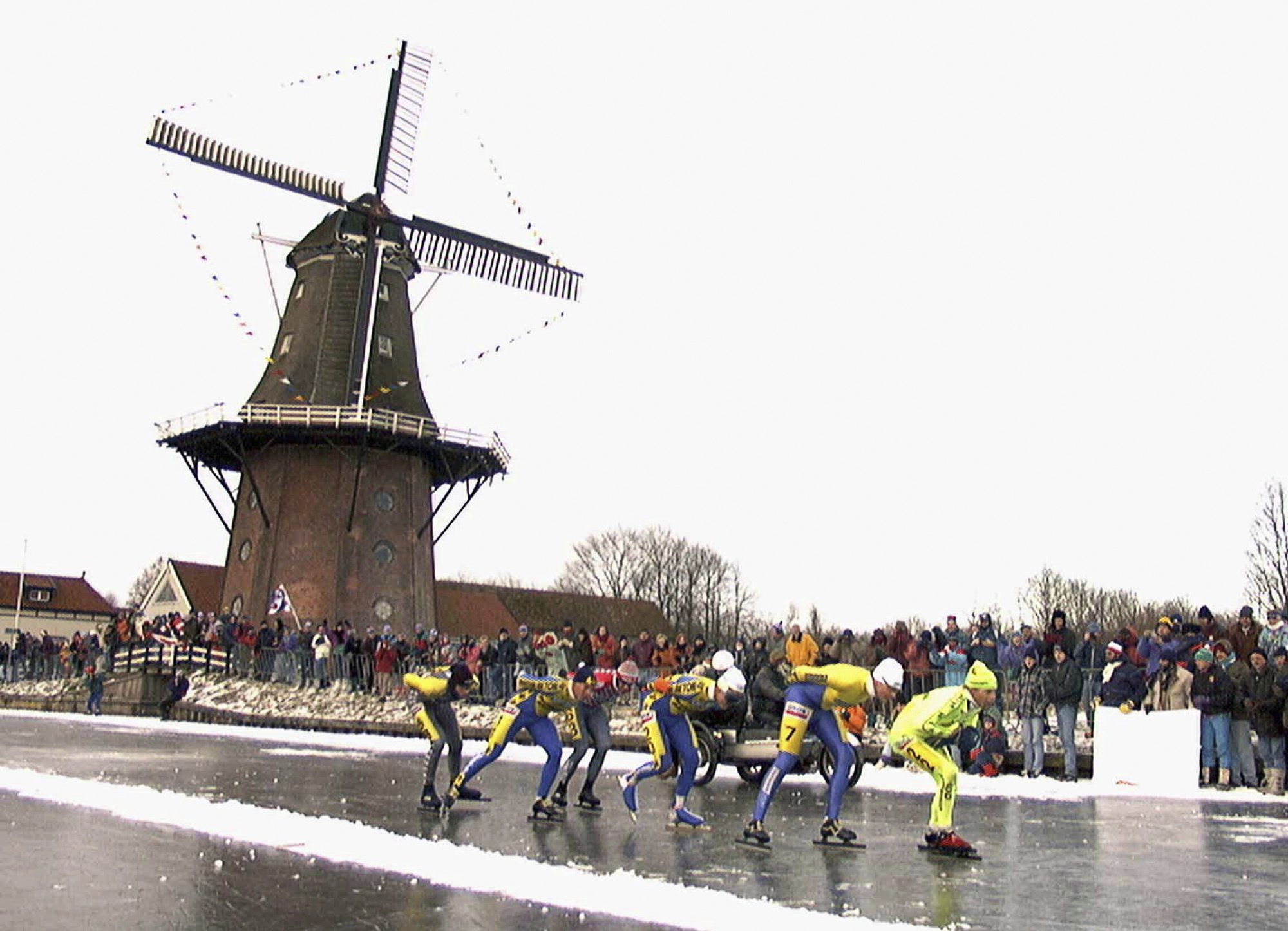 In this Jan. 4, 1997, file photo, skaters pass a windmill as some 16,000 people participate in the historic 200km skating spectacle the 'Elfstedentocht' (eleven-cities-course) in Birdaard, province of Friesland, northern Netherlands. There is nothing more mythical in Dutch sports than an age-old 11-city race skating across lakes and canals in bone-numbing cold from dawn to dusk. (AP Photo/Dimitri Georganas, File)