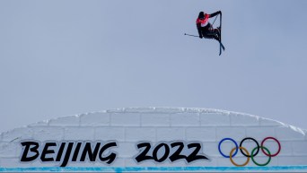 Teal Harle grabs his ski while going over a big snow bank labelled with Beijing 2022