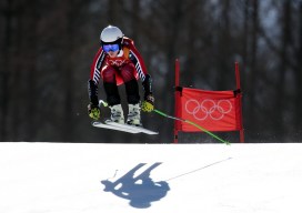 Alpine skier and her shadow going over a jump