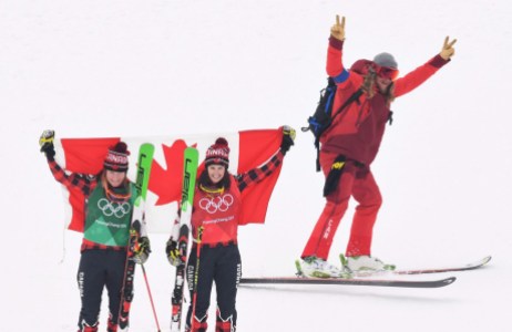 OLY FRE Skicross Canada 20180223 Gold medalist Kelsey Serwa, right, and silver medalist Brittany Phelan both of Canada celebrate as a skier passes by following the women's ski cross final at the Phoenix Snow Park at the 2018 Winter Olympic Games in Pyeongchang, South Korea, Friday, Feb. 23, 2018. THE CANADIAN PRESS/Jonathan Hayward