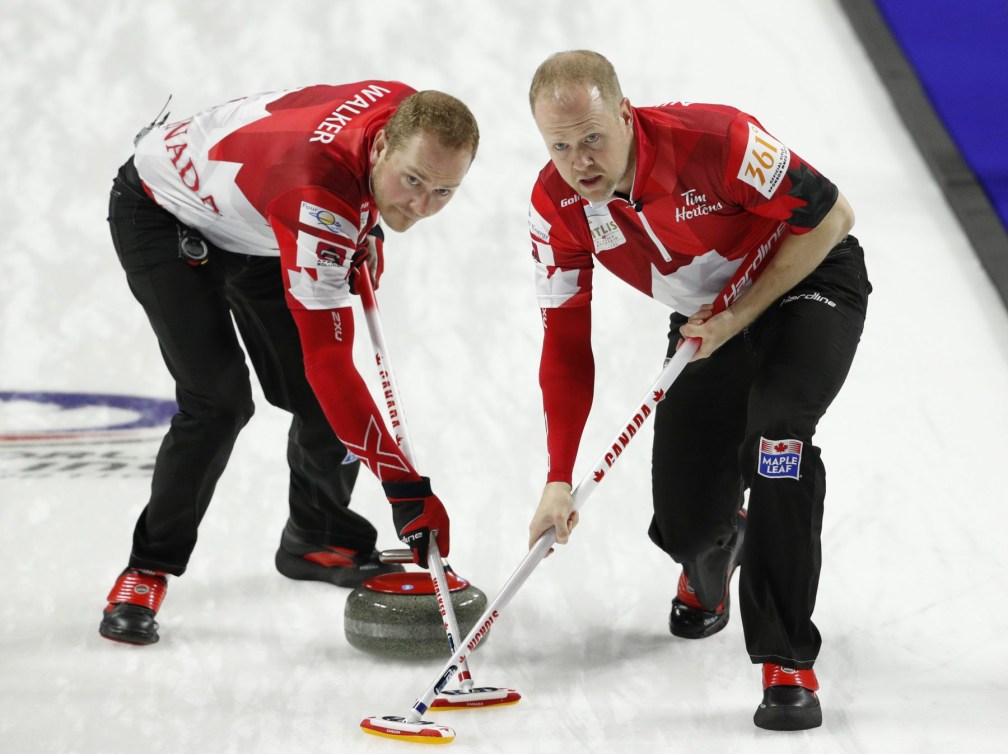 Geoff Walker, d'Équipe Canada, à gauche, et Mark Nichols brossent une pierre lors d'un match contre les États-Unis au Championnat du monde de curling masculin, le samedi 7 avril 2018, à Las Vegas.