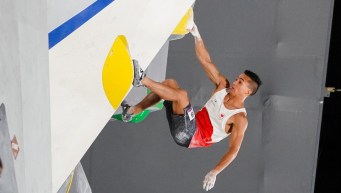 Sean McColl holds onto a yellow hold during a bouldering route