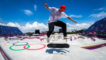 Skateboarder flips his board under his feet on top of the Olympic rings