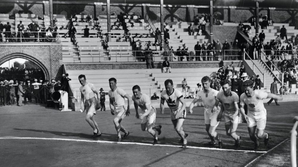 Black and white photo of sprinters running from start line