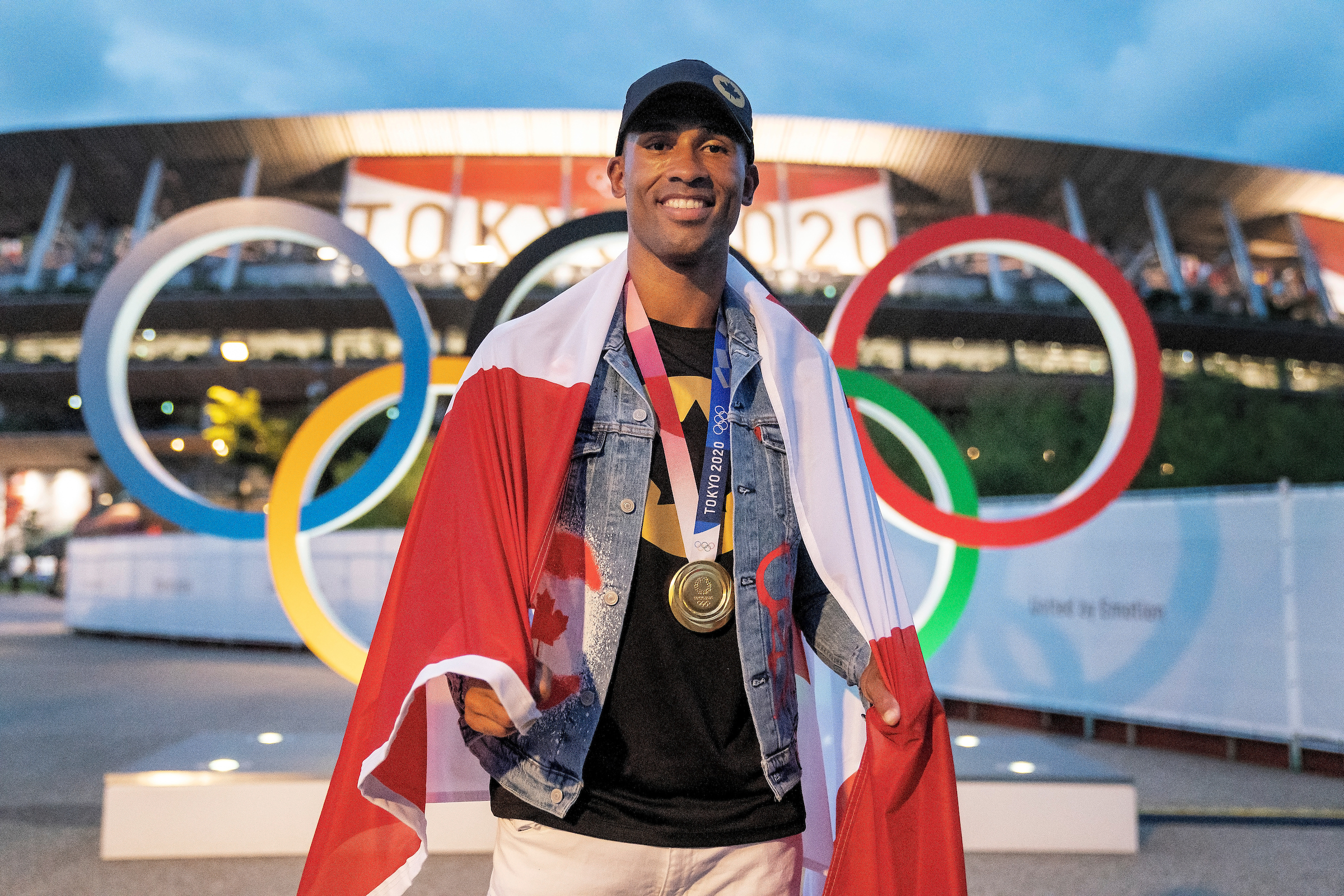 Damian Warner poses with the Canadian flag on his shoulders while wearing his gold medal