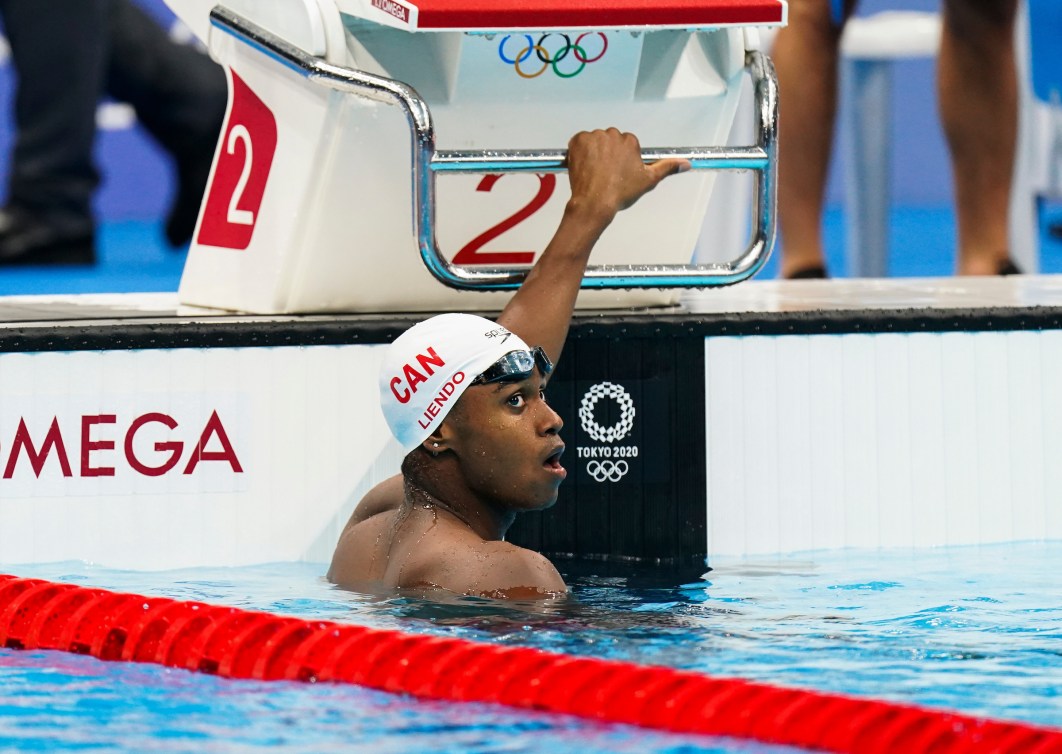 Joshua Liendo holds onto the start block while in the water of the pool 