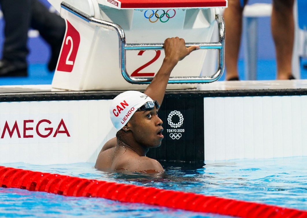 Joshua Liendo holds onto the start block while in the water of the pool