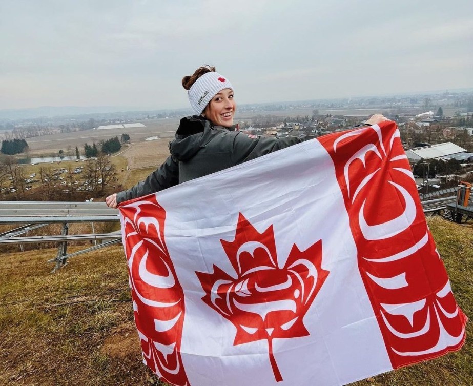 Alexandria Loutitt poses with the Canadian Indigenous Flag while competing at a FIS World Cup Ski Jumping event in Austria in February 2023. 