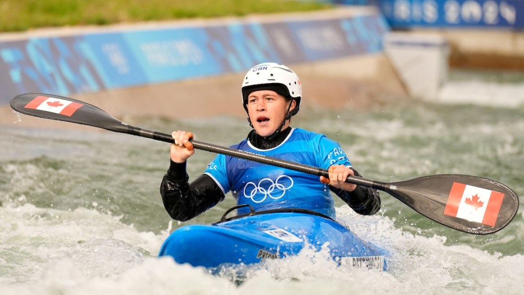 Lois Betteridge competes in canoe cross while wearing a blue jersey