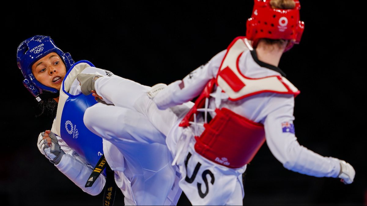 Skyler Park con una chaqueta azul patea a su oponente con una chaqueta roja en un partido de taekwondo.