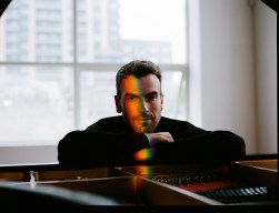 Man sitting at piano with rainbow light on face