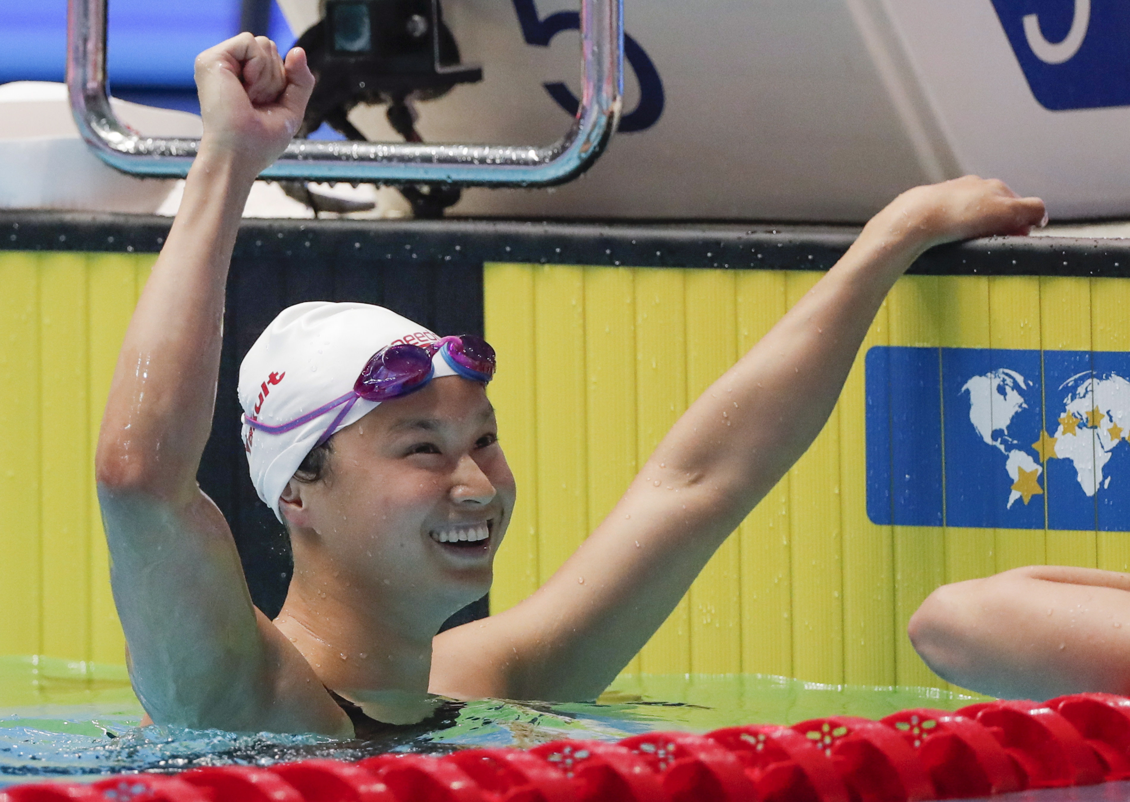 Maggie MacNeil raises a fist in celebration after winning the women's 100m butterfly title.