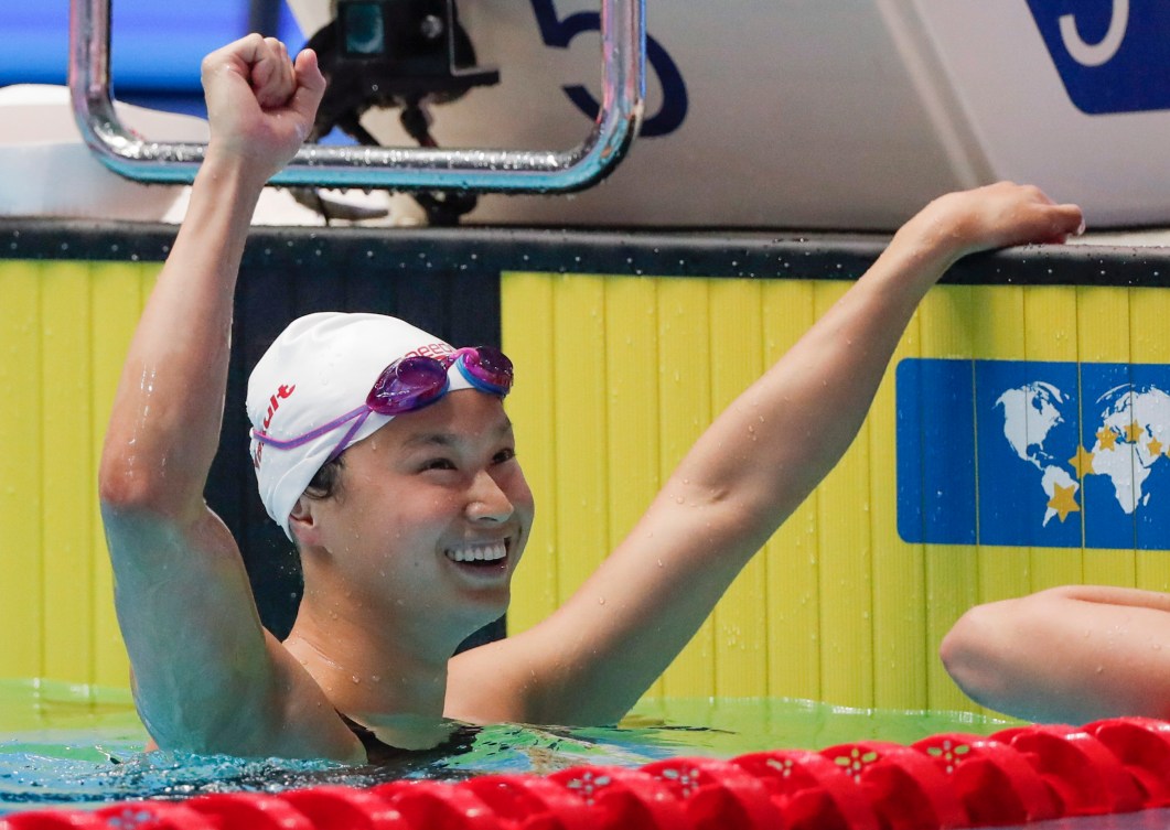 Maggie MacNeil raises a fist in celebration after winning the women's 100m butterfly title.