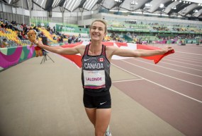 athlete smiles holding the Canadian flag