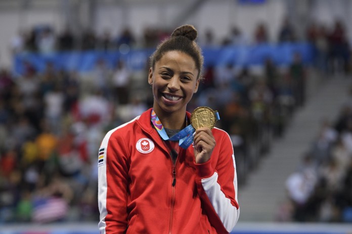 jenn abel holds up her gold medal and smiles