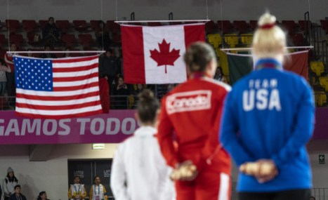 team-canada-samantha-smith-2 three athletes stand on the podium with the american and canadian flags in the distance
