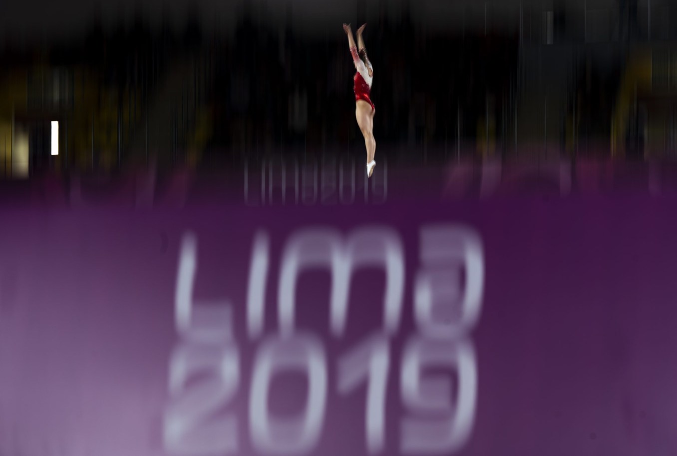 athlete in the air above a lima 2019 sign