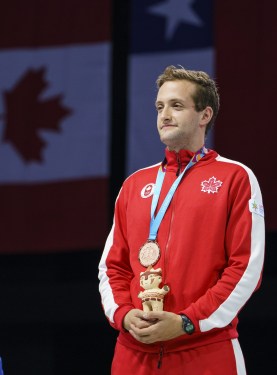 man stands on podium with a medal