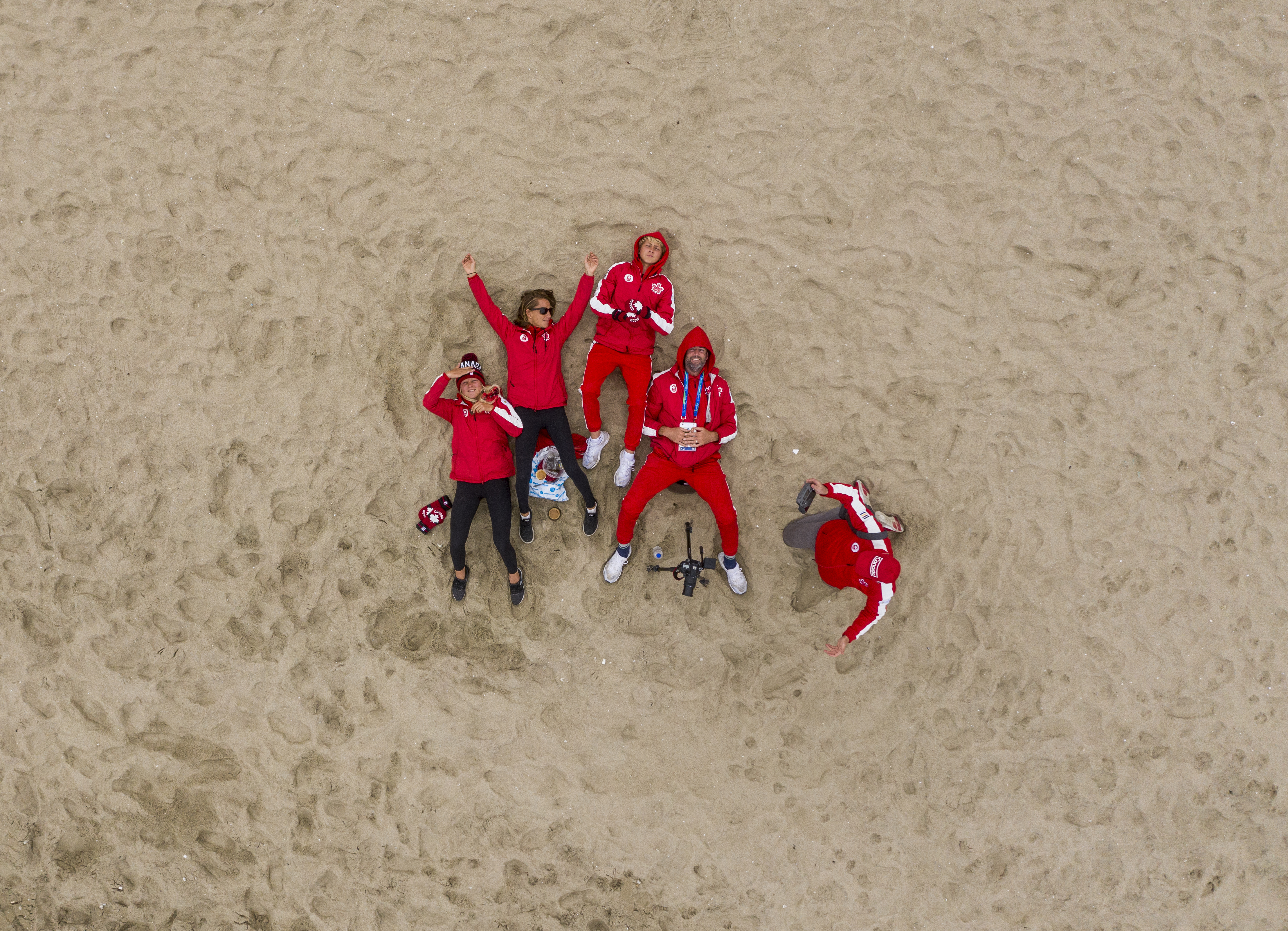 Surfers in their Team Canada Kits lay on the sand