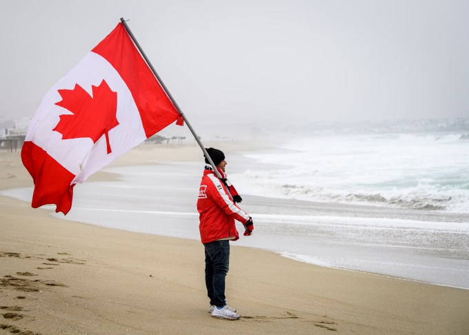 Team Canada coach holding a Canadian flag