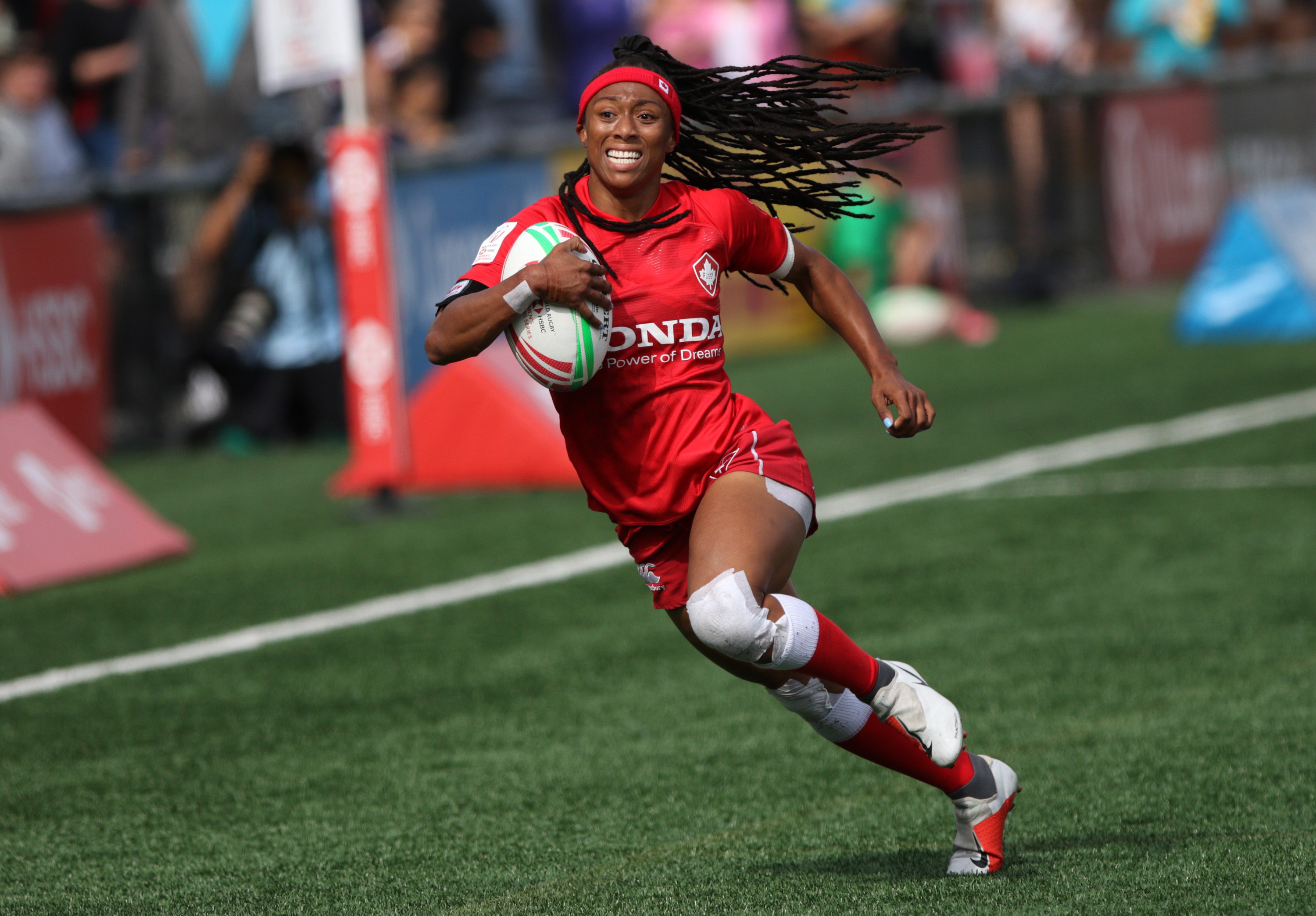 Charity Williams holds the rugby ball and runs.