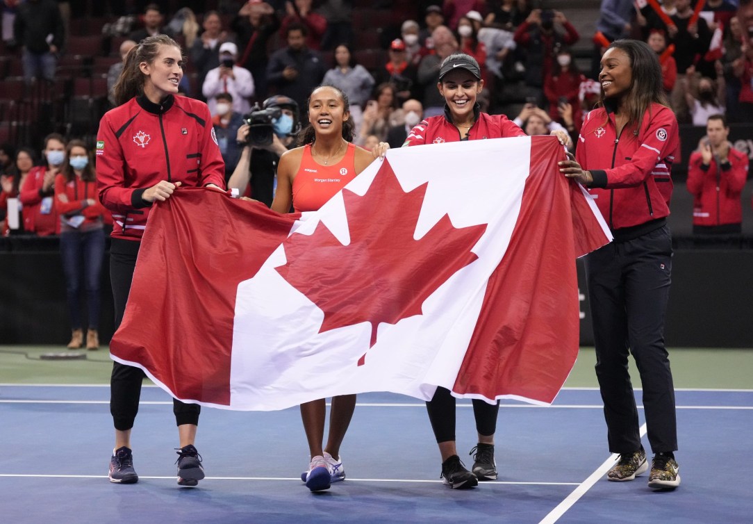 Team Canada tennis players hold the Canadian flag 