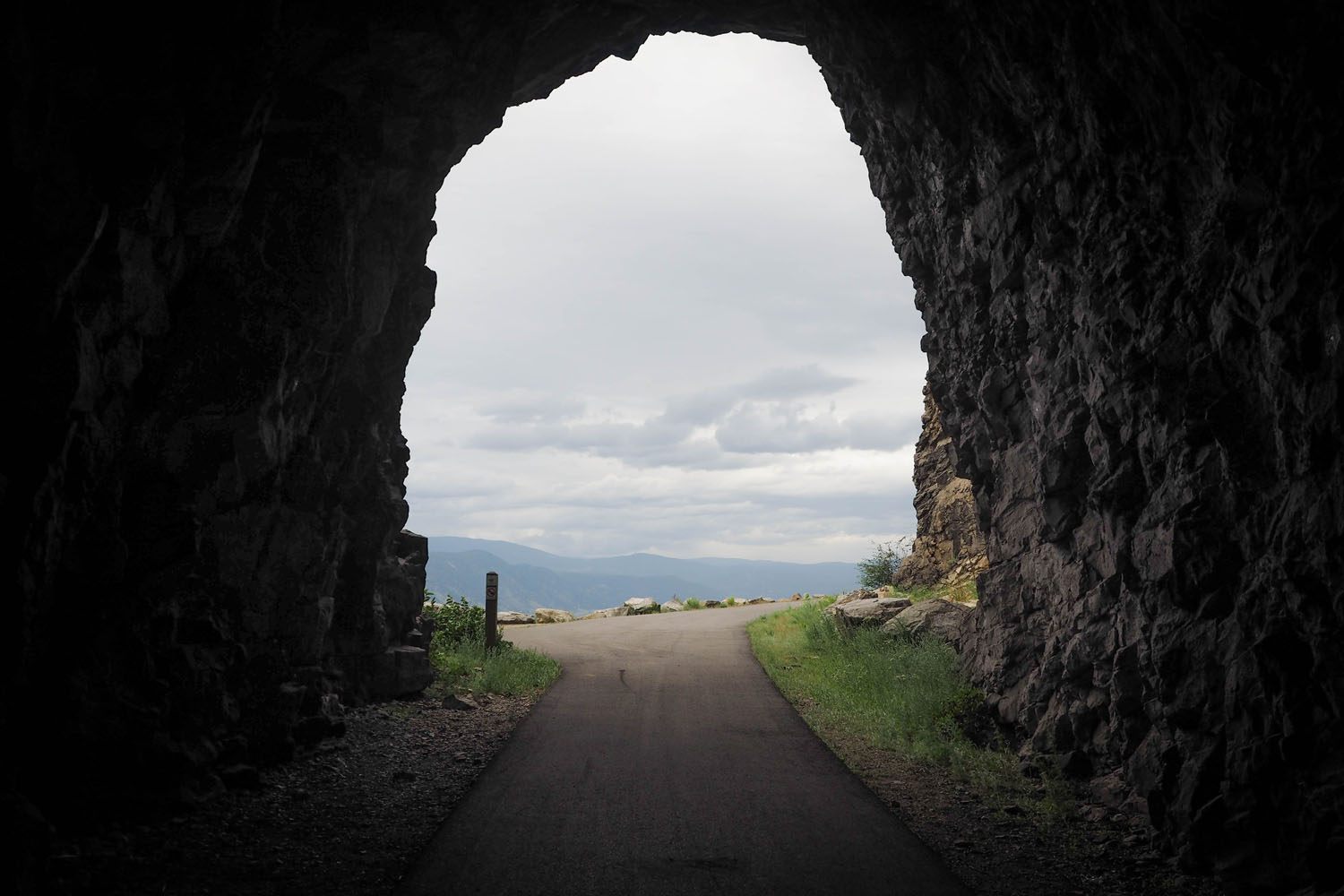 Looking through tunnel on bike trail. Looking out to hills and horizon in BC