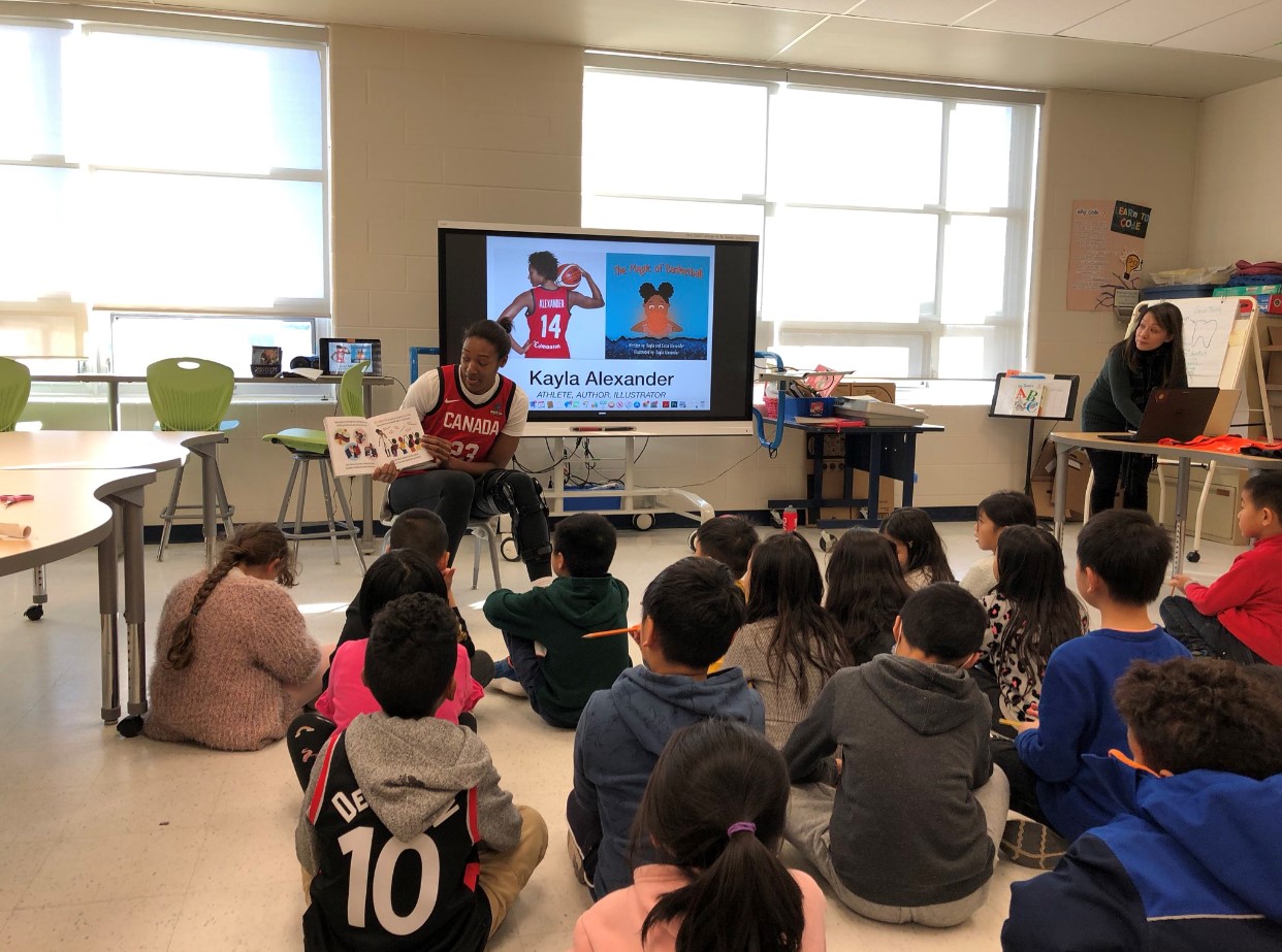 Kayla Alexander reads her book to children in a classroom