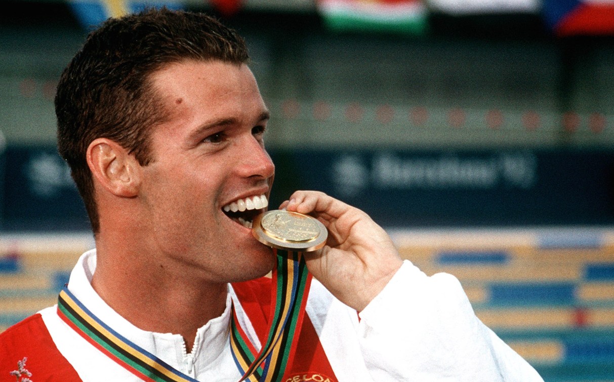 Mark Tewksbury bites medal after winning the gold medal