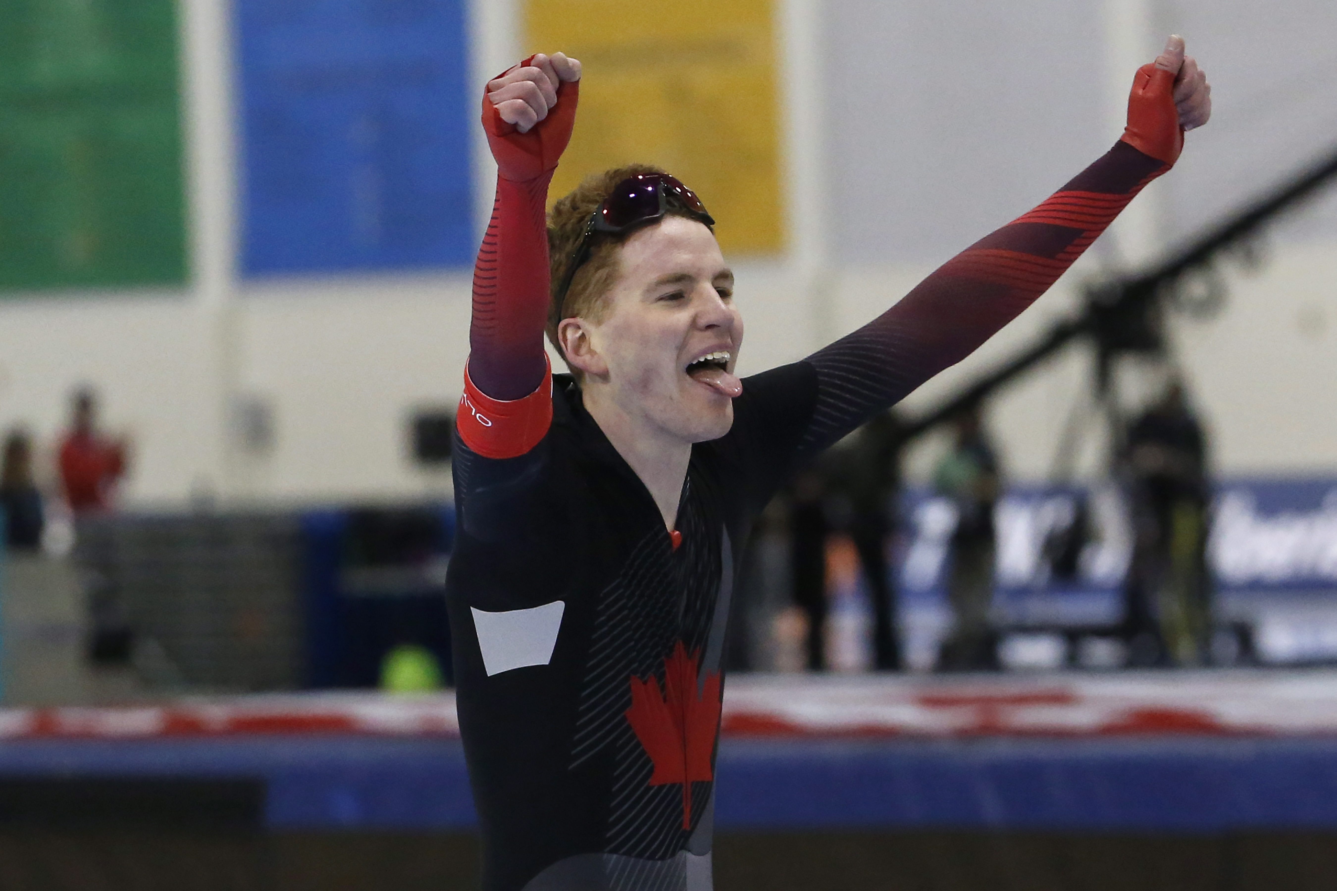 Speed skater holds his arms up in the air in celebration 